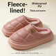 A pair of pink fleece-lined slip-on slippers with quilted stitching and a soft pink interior, shown on a light beige background with promotional text reading 'Fleece-lined!', 'Waterproof PU Thick and warm', and 'WINTER WARM COTTON SLIPPERS'.