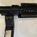 Black handheld brush with bristle head on a white background