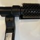 Black handheld brush with bristle head on a white background