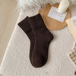 Brown sock on a textured surface with a candle and card in the background