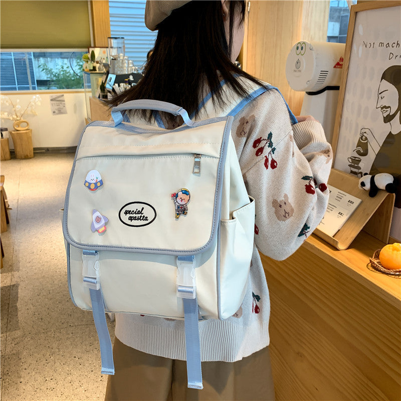 Person wearing a white backpack with blue straps in an indoor setting