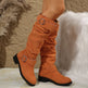 Orange knee-high boots with metal buckles on a textured surface