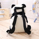Panda-shaped plush toy with black straps on a wooden surface