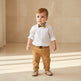 Child wearing a white shirt with a bow tie and tan pants, with separate images of the shirt and pants on a white background.