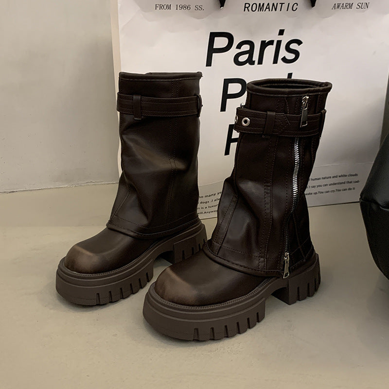 Pair of black leather boots with zippers on a light background