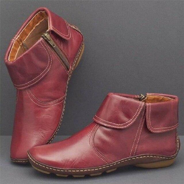 Pair of red leather ankle boots on a gray background