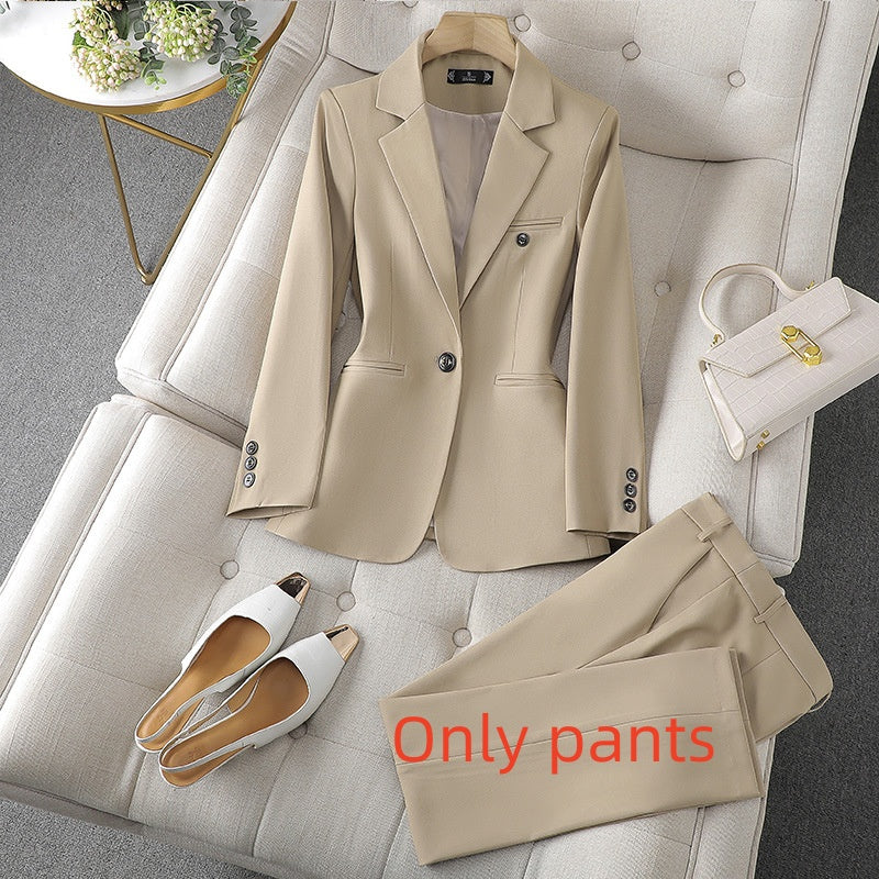 Beige suit jacket and pants on a gray sofa with white shoes and a handbag.
