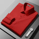 Folded red shirt on a gray surface with a white watch.