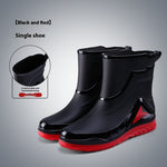 Black rain boots with red soles on a gray background