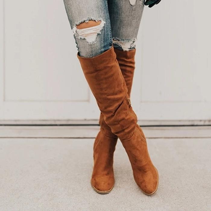 Brown knee-high boots worn with ripped jeans on a light background