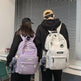 Two people wearing backpacks with a neutral background
