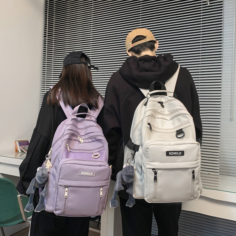 Two people wearing backpacks with a neutral background