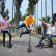 Three young men riding electric scooters on a street with palm trees in the background
