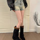 Person wearing black knee-high boots with leopard print trim, denim shorts, and a dark jacket indoors.