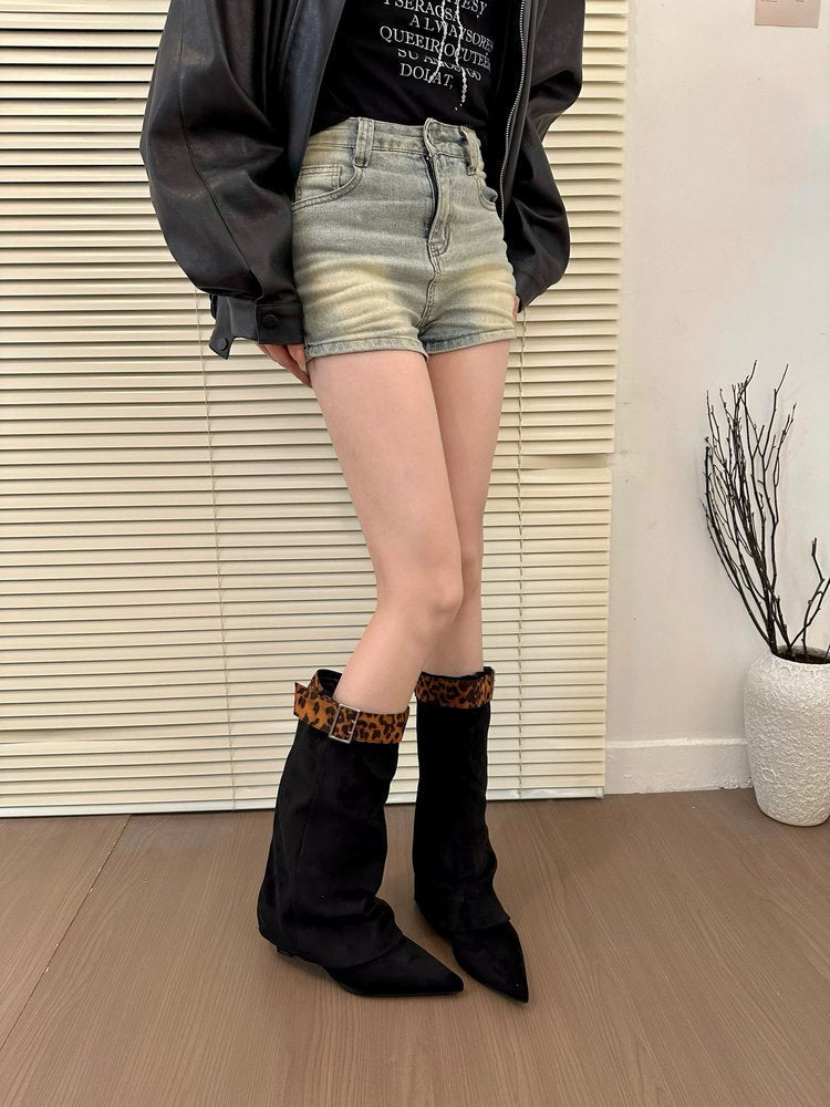 Person wearing black knee-high boots with leopard print trim, denim shorts, and a dark jacket indoors.