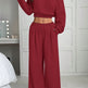 Person wearing a red outfit with a matching top and wide-leg pants in a room.
