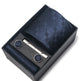 Navy blue tie set with cufflinks and a clip in a black box on a white background