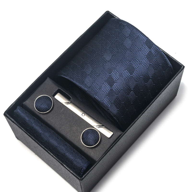Navy blue tie set with cufflinks and a clip in a black box on a white background