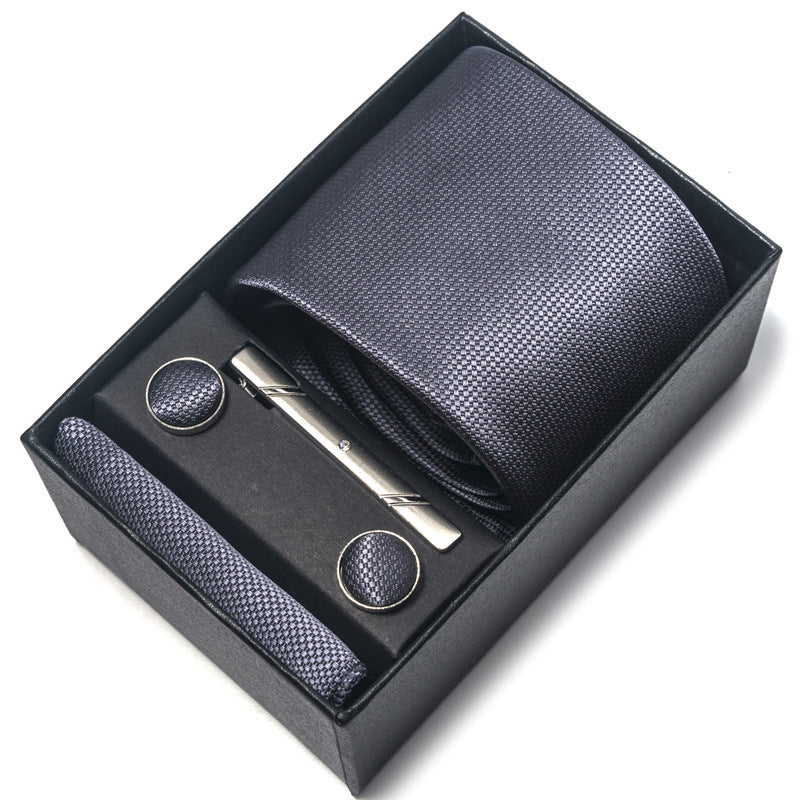 Black textured tie set with tie clip and pocket square in a box on a white background