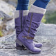 Purple boots with zippers and a buckle worn on a rocky surface