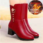 A pair of red faux-leather ankle boots with a chunky black block heel, featuring a decorative gold-tone crescent moon and flower charm on the outer side. The boots are shown on a model's foot, with a circular graphic overlay in the top right showing flames and the text 'Heat storage and warm winter series'.