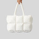 White quilted tote bag held by a hand on a light gray background