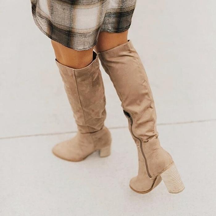 Beige knee-high boots worn with a plaid skirt on a light background