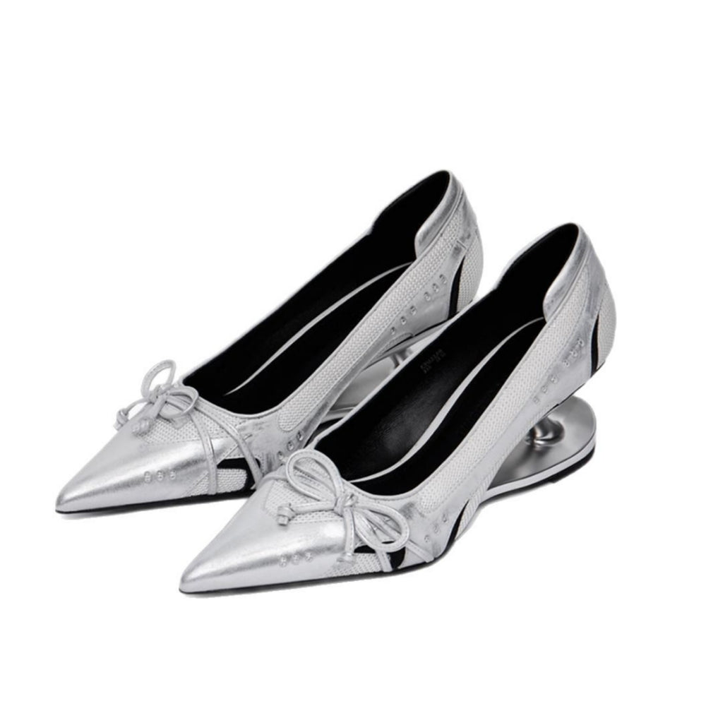 A pair of metallic silver pointed-toe pumps with low block heels, decorative bow details on the toes, and a glossy black interior, shown against a plain white background.