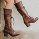A pair of knee-high brown leather lace-up boots with block heels, worn on a person's feet against a light concrete floor.