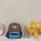 Children's backpack with a red and blue design on a white surface with decorative items.