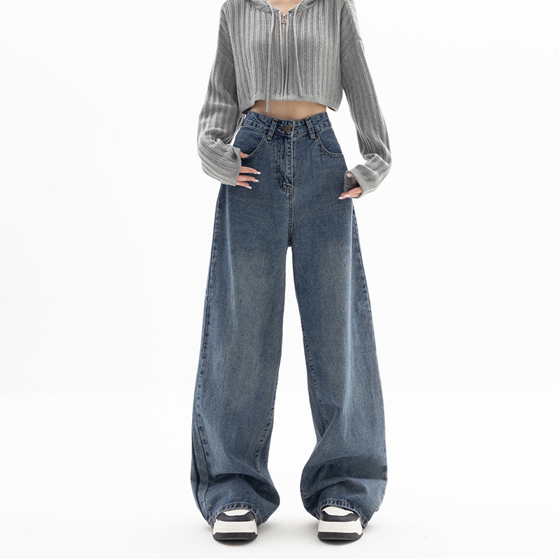 Person wearing a gray pleated shirt and blue jeans on a white background