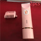 Pink hair trimmer with a comb on a red background