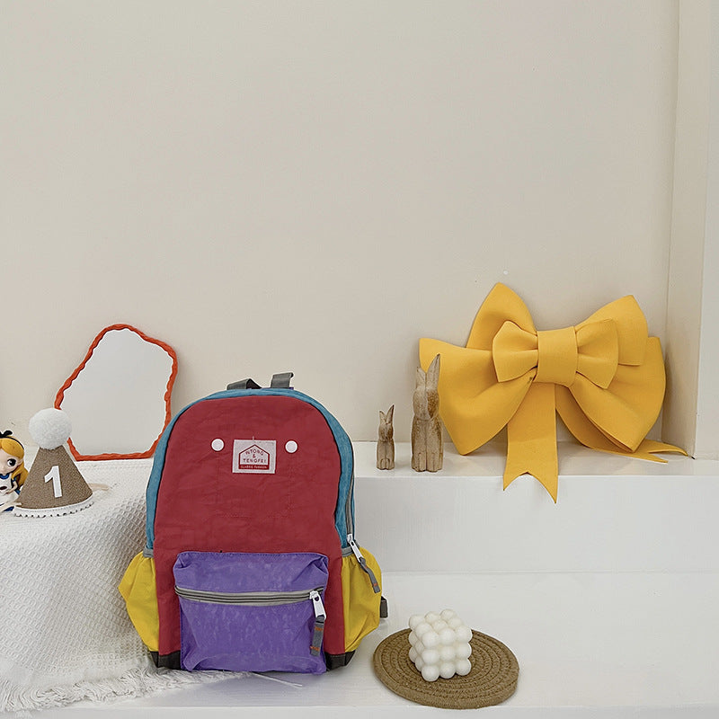 Colorful backpack with purple compartment on a white surface with decorative items.