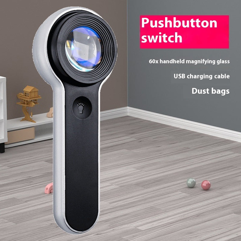 Handheld magnifying glass with pushbutton switch on a wooden floor.