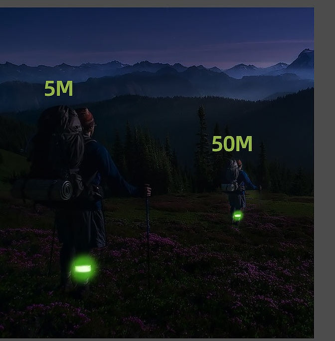 Two people with backpacks and glowing devices in a mountainous landscape at night.