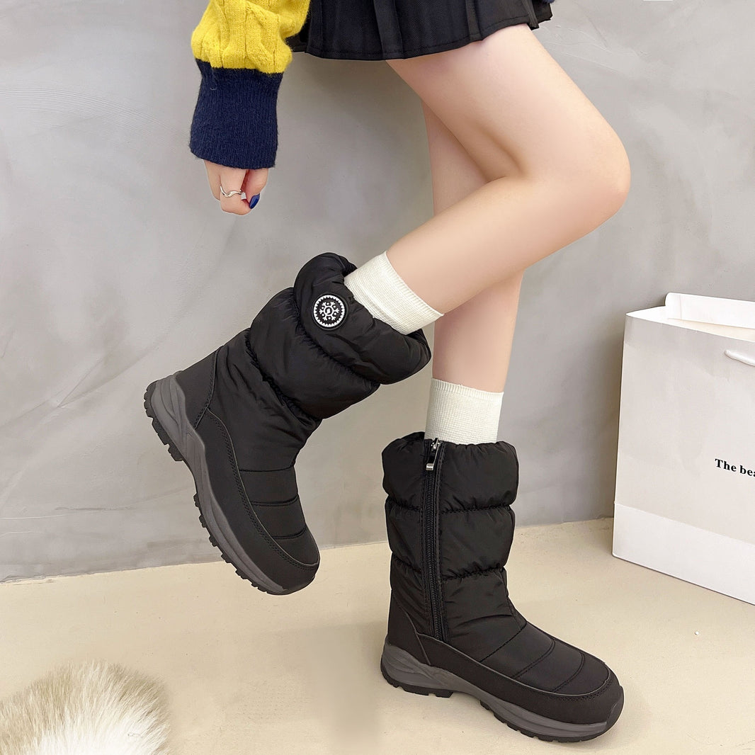 Person wearing black winter boots with a plain background