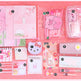 A pink stationery set arranged on a pink background, including notebooks, pens, a glittery pencil case, a small Hello Kitty-themed item, a notepad, and other cute pastel accessories.