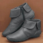 Pair of gray ankle boots with a zipper on a brown background