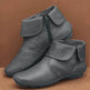Pair of gray ankle boots with a zipper on a brown background