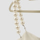 Pearl necklace draped over a white garment on a light gray background