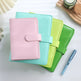 Three colorful planners stacked with a pen on a light surface