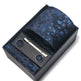 Tie, tie clip, and cufflinks set with blue floral pattern in a black box on a white background