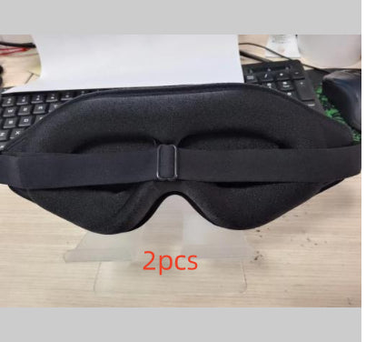 Black eye mask on a stand with '2pcs' text, keyboard in the background