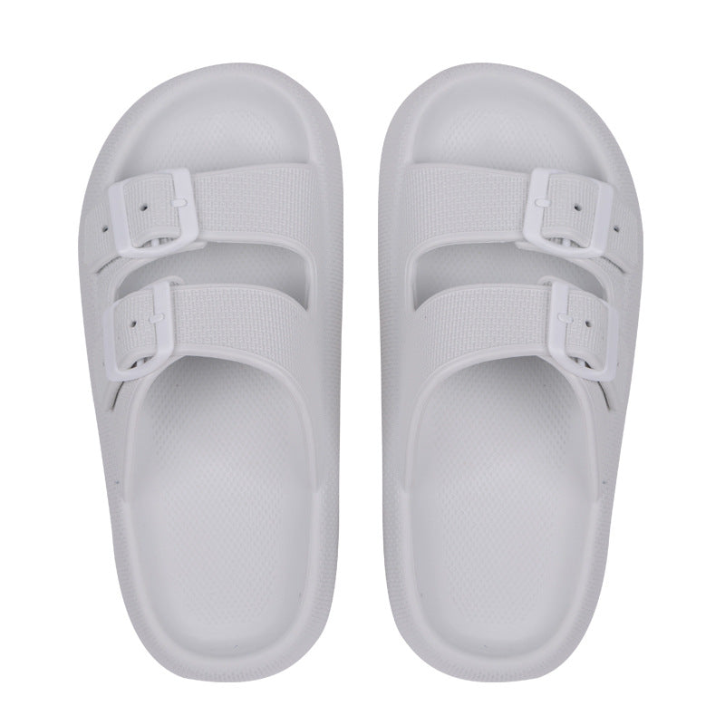 Pair of white slides with buckles on a white background