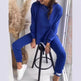 Person wearing a blue outfit sitting on a black stool indoors.