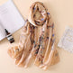 Floral patterned scarf on a beige surface with a bottle and card.