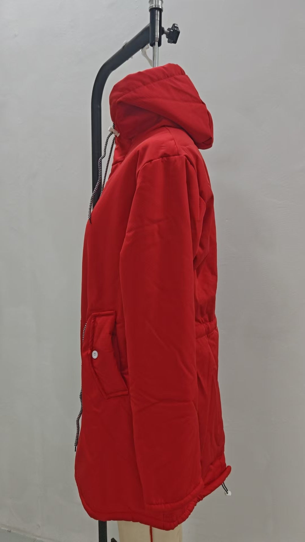 A bright red hooded puffer jacket displayed on a black clothing hanger against a plain light gray wall.
