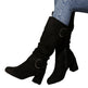 Black knee-high boots with circular buckles worn by a person on a white background