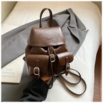 Brown leather backpack on a light surface with a gray garment
