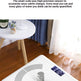 A white digital body scale with a small blue display screen is shown on a wooden floor in a home setting, with a small table and curtains nearby. Text at the top describes high-precision sensors and weight measurement.
